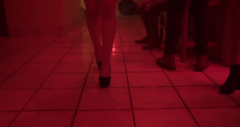 Woman in high heels walks on a corridor under red lights