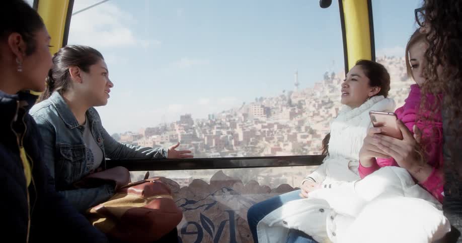 Five young women ride in a cable car up a mountain