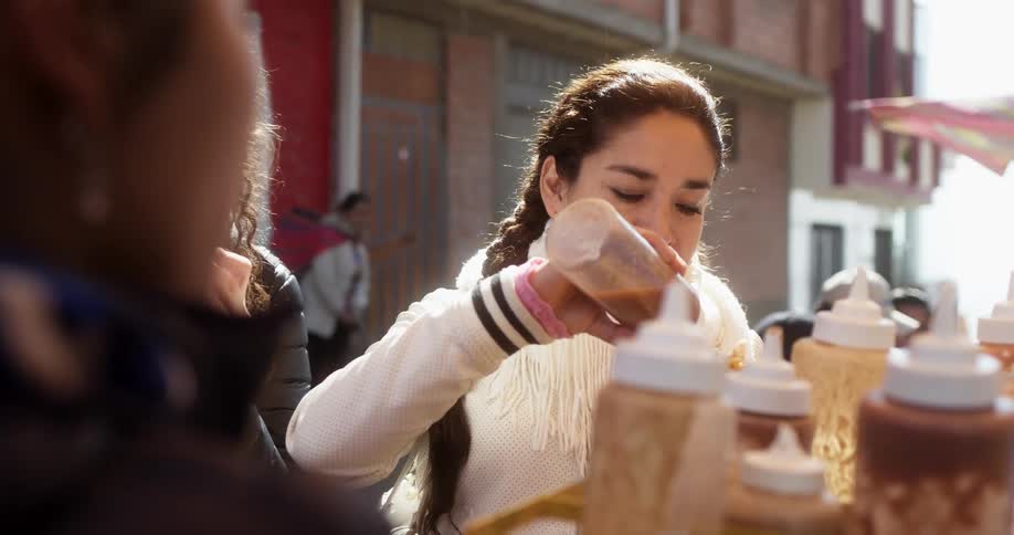 A woman puts sauce on her food while others are eating