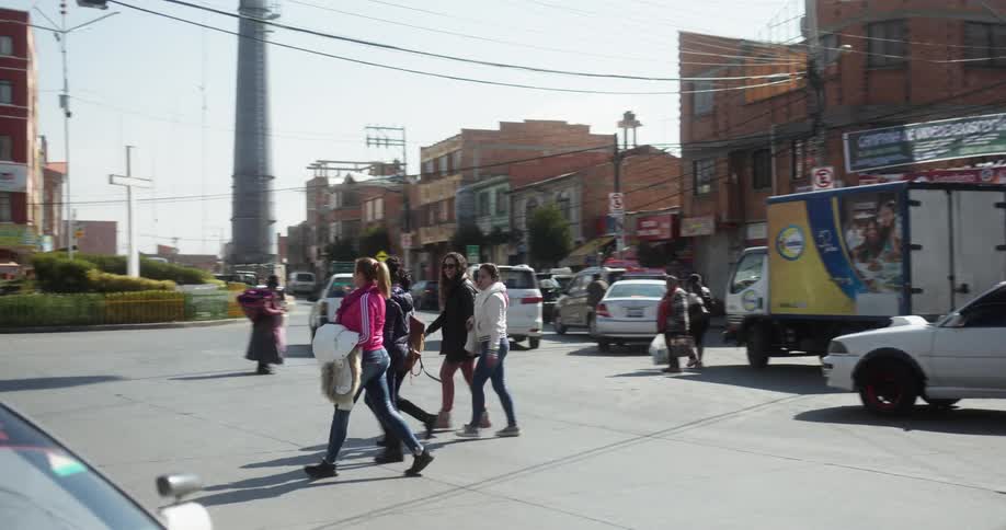 A group of young women walk across a parking lot in an urban neighborhood