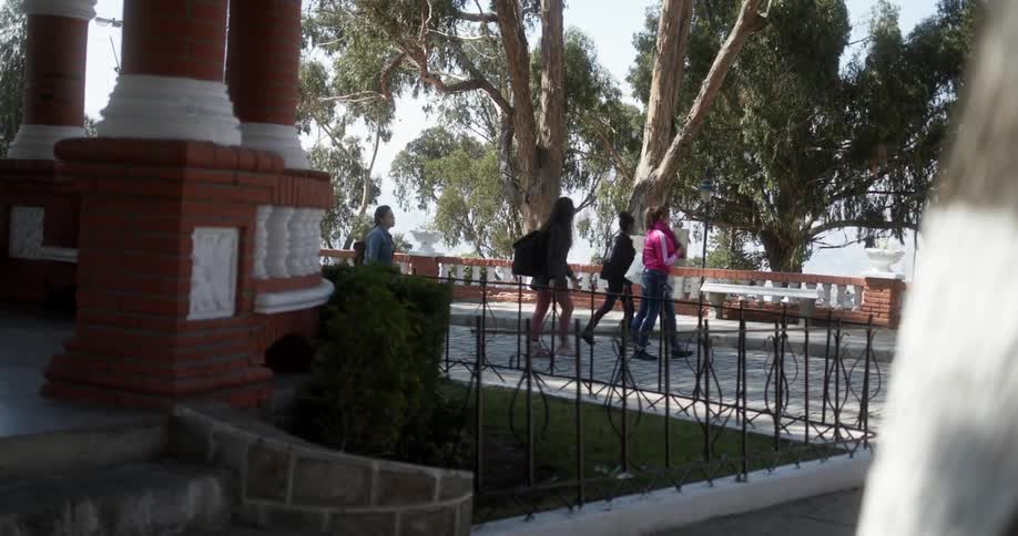 A group of young women walking away from a building together while carrying bags