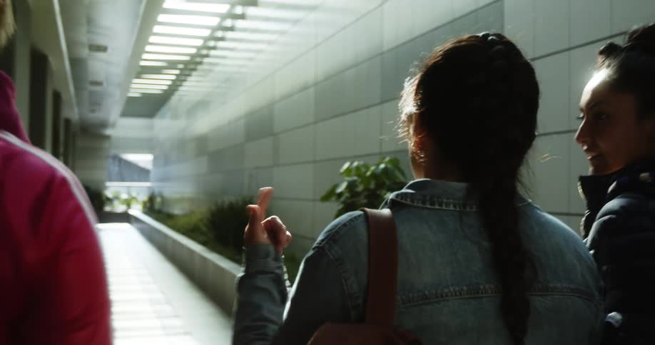 A group of young women walk down a tunnel lit up by a skylight