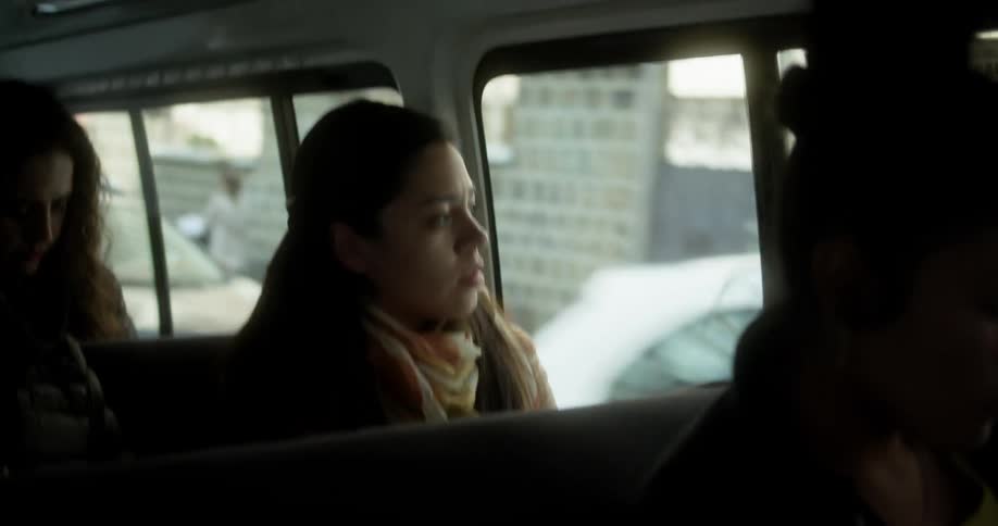 A woman looks out the window as the bus shes riding in passes through a city neighborhood