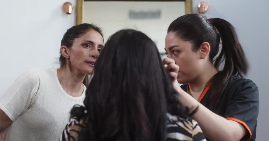 Technician consults with another woman as she examines the face of a third woman