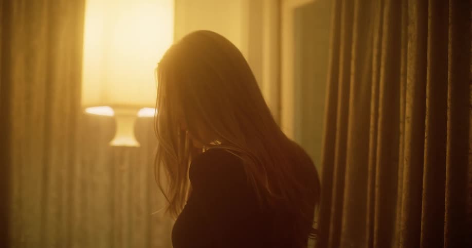 Blonde woman takes off her fur coat and turns around in the bedroom