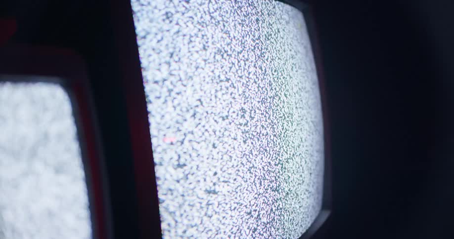 Television screens show static in a dark room