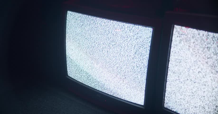 The televisions flicker static in the dark