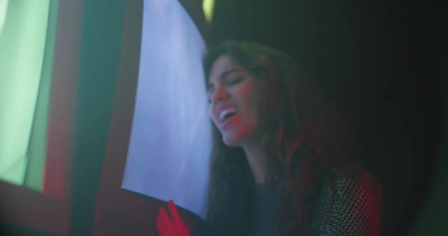 A woman sings and dance while touching a television screen