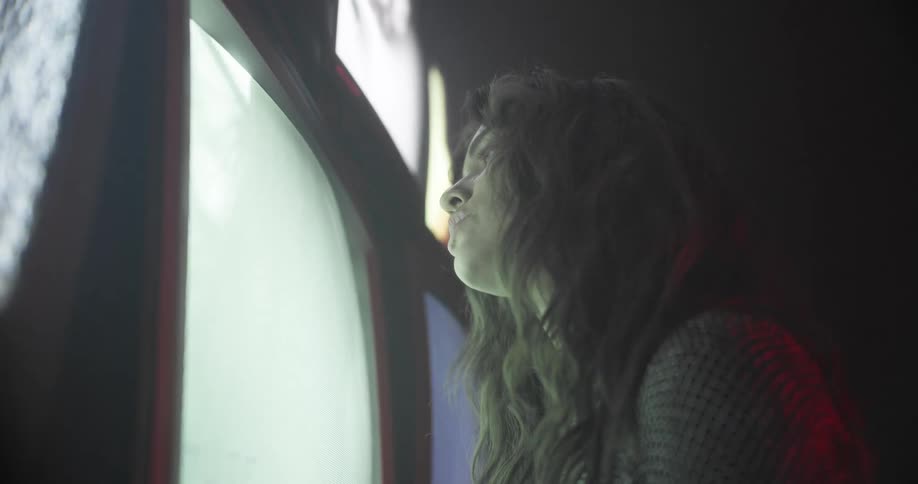 Woman sings as she walks towards a bank of monitors