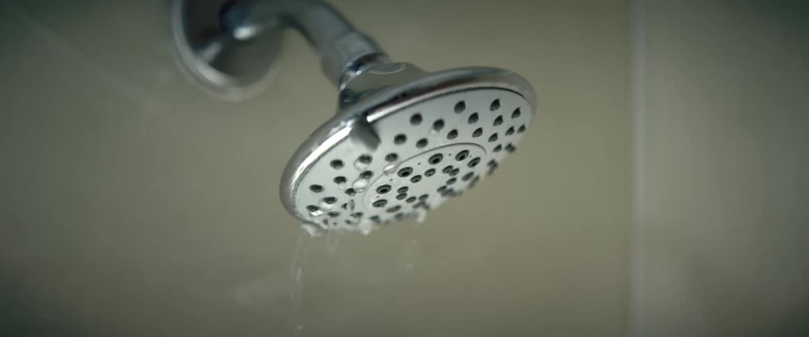 Water spraying and then dripping from a showerhead as the water flow is decreased