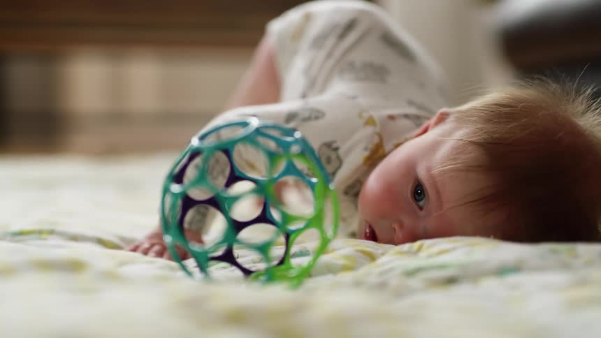 Baby attempting to crawl to a plastic ball