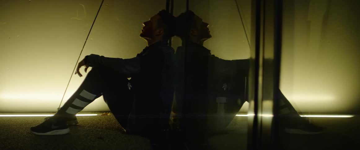 A man sitting on the floor next to a mirror and a light