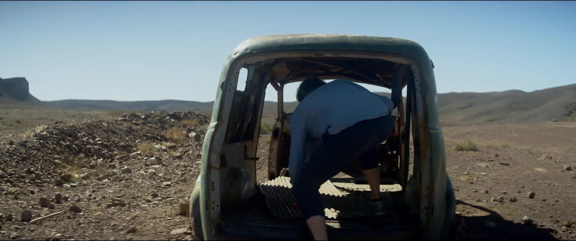 A man discovers and explores an old abandoned vehicle in the middle a large basin