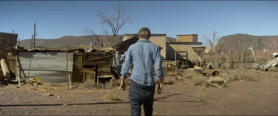 A man walks towards an old building in a rural area