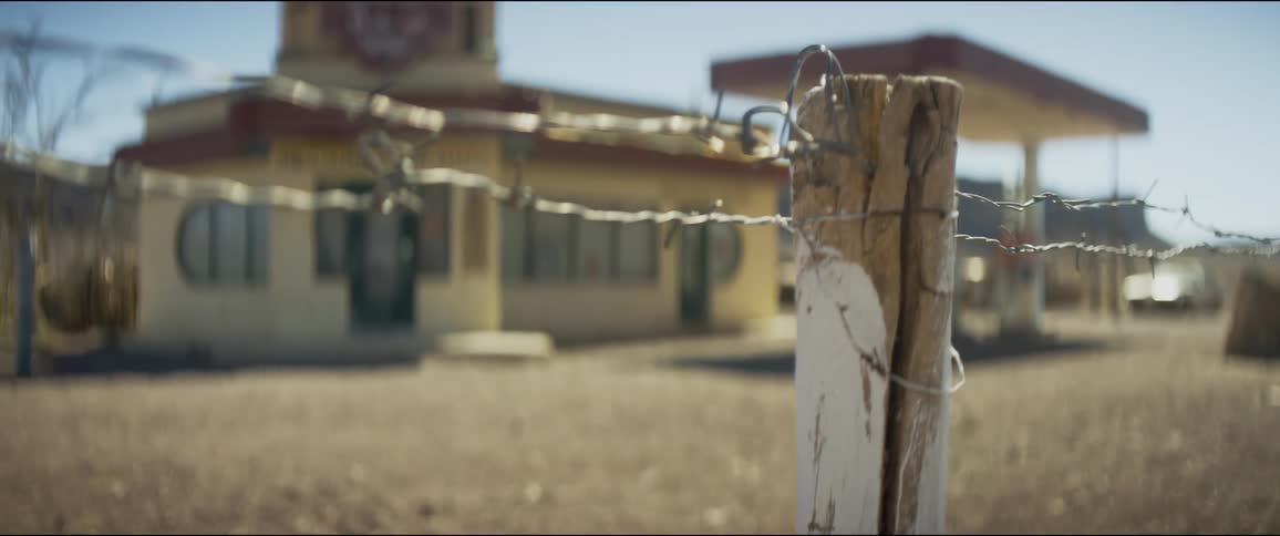 Wired fence on a wooden pole in front of a gas station in the desert