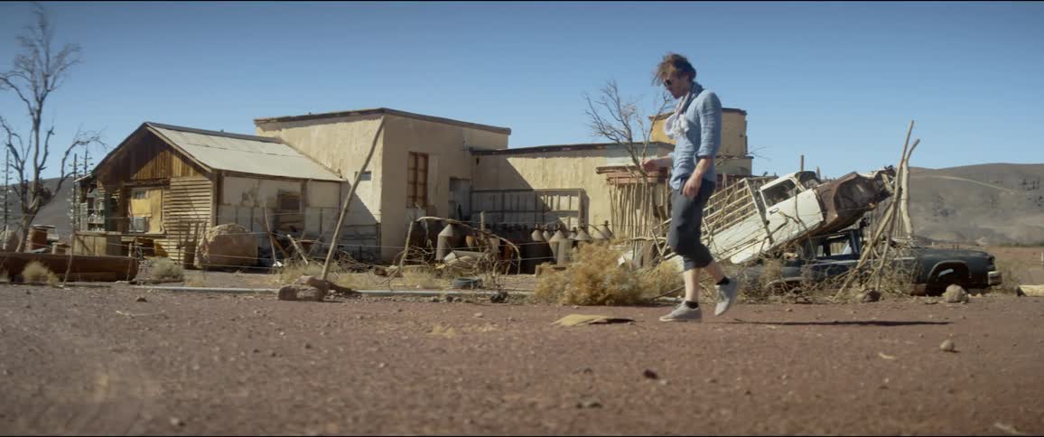 Young blonde man wearing sunglasses walks on a rural area