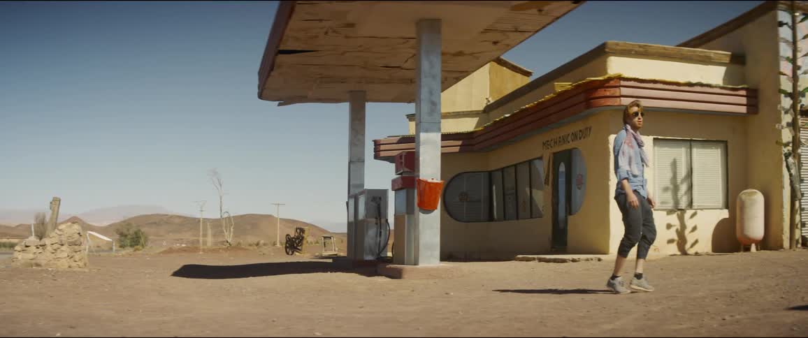 Man walks around abandoned gas station in desert
