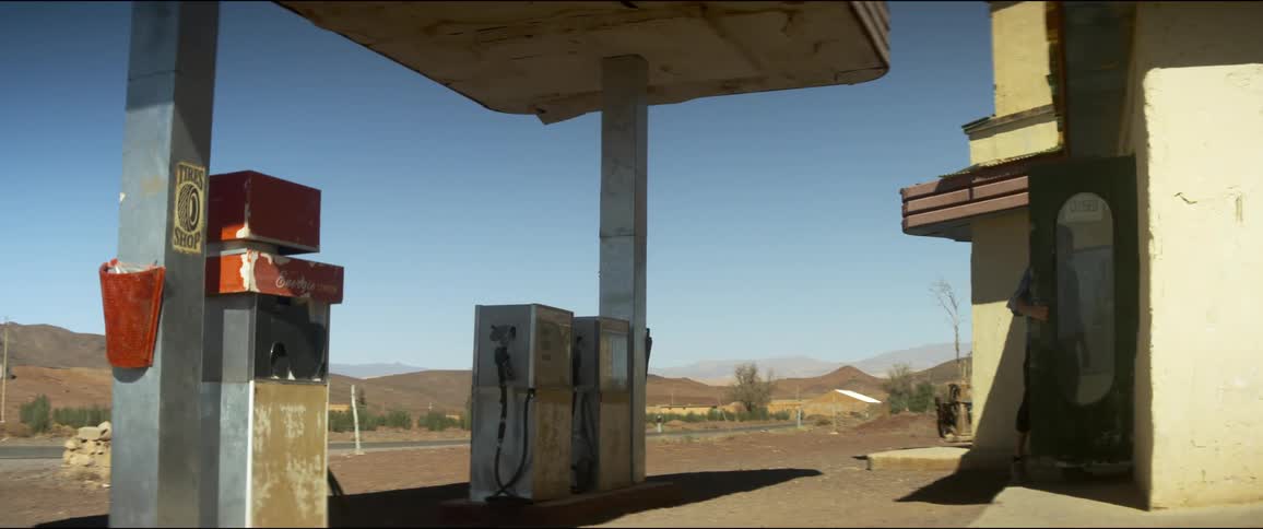Young man enters convenience store in a gas station located in a road in the desert