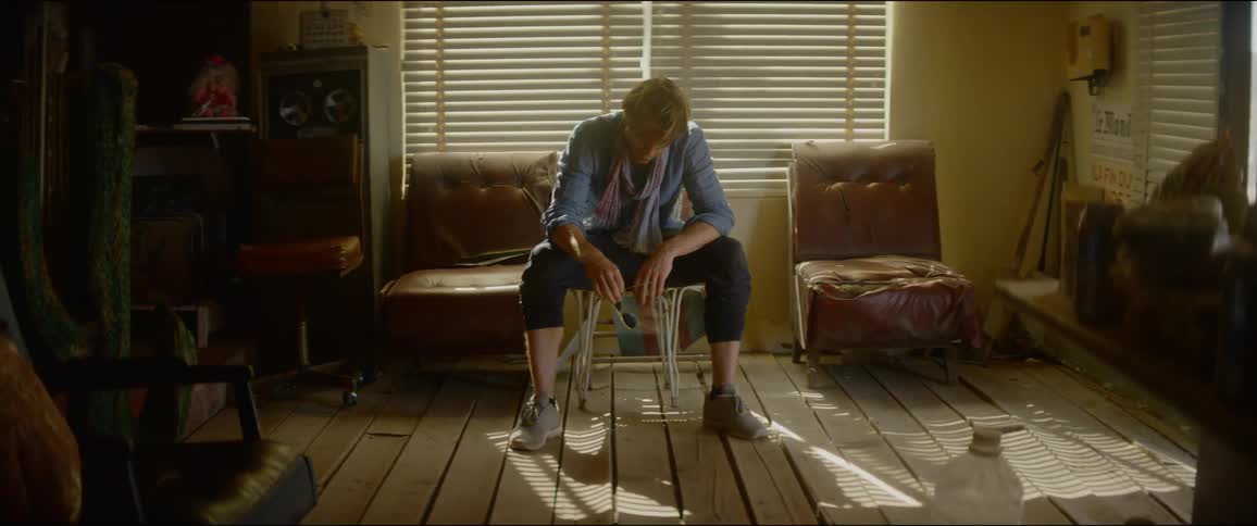 A man sitting on a chair in a room with windows behind him