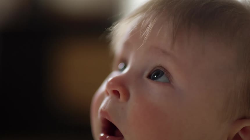 Blonde hair baby boy looks up with his mouth open