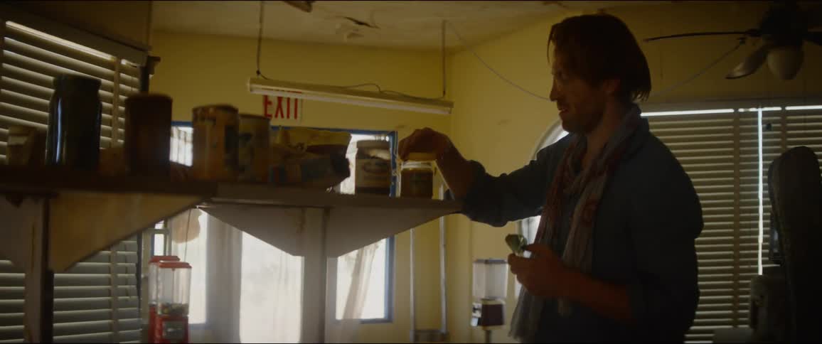 A white man stands in a restaurant and sniffs a jar on a shelf