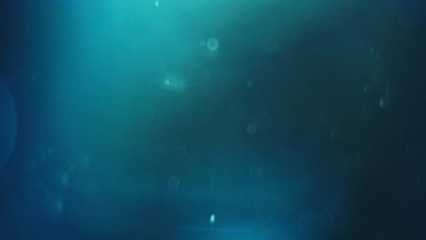Particles of white dust slowly falling against an aquamarine blue background
