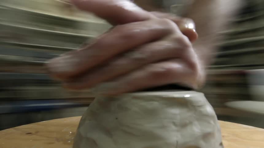 A person shaping clay on a spinning sculpting turntable
