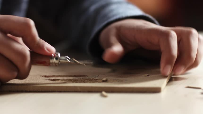 Man uses a sharp leatherworking tool to carve a piece of leather