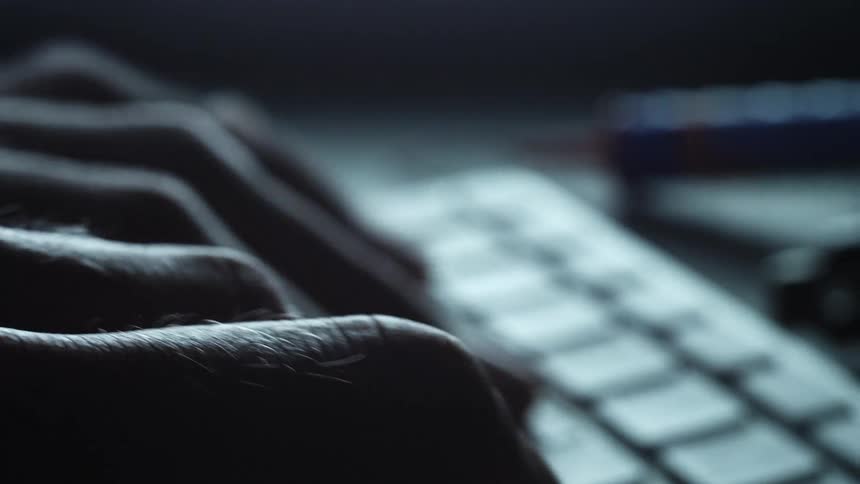 Fine hairs can be seen on hands typing on computer keyboard in shadows