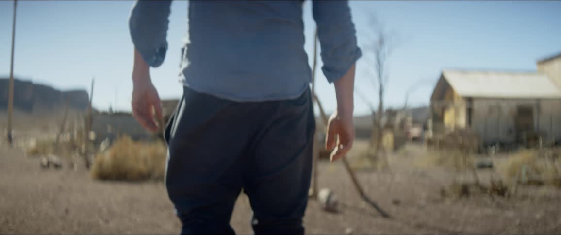 Person walks in front of run down buildings in rural area