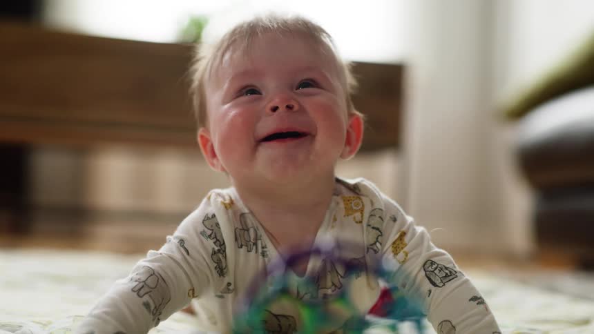 Happy baby laughing laying on his tummy on the floor