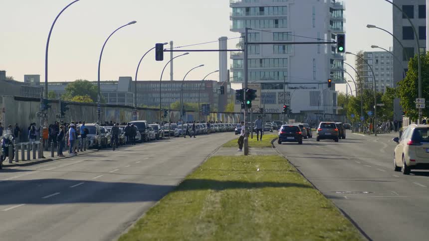 Traffic travels on the road while pedestrians and a bicyclist are nearby
