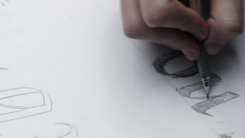 A person shades in letters on paper