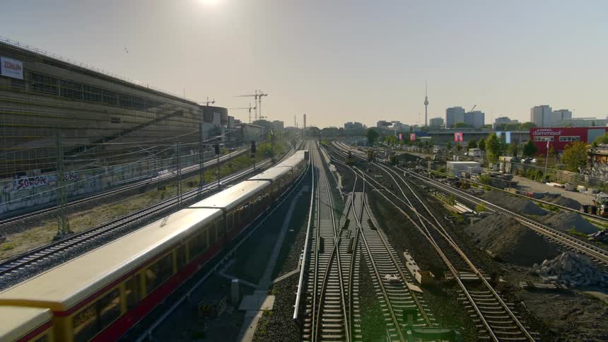 Train tracks with trains running on them with the city skyline in the background