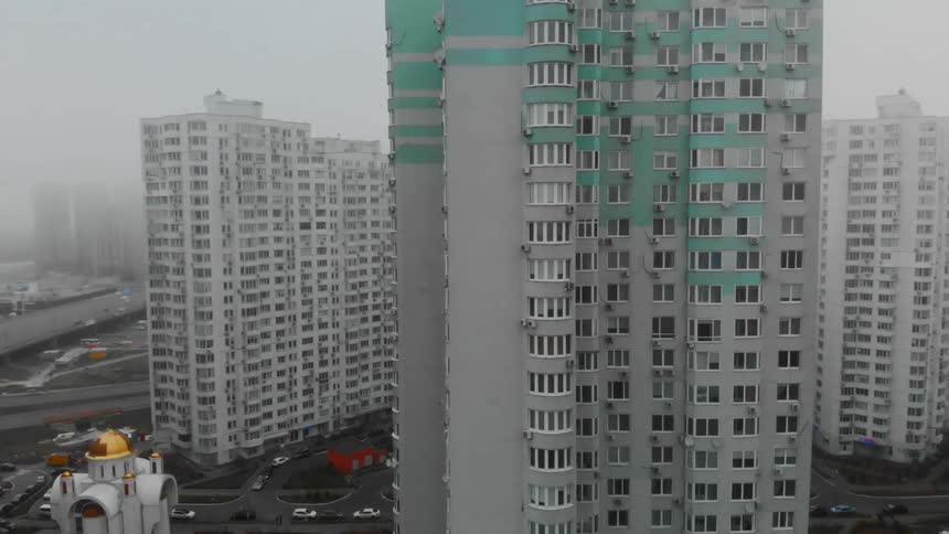 A gray skyscraper with its upper floors marked with turquoise paint in a metropolis during the day