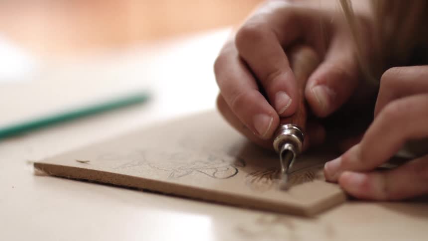 Designs being carved into a flat piece of wood