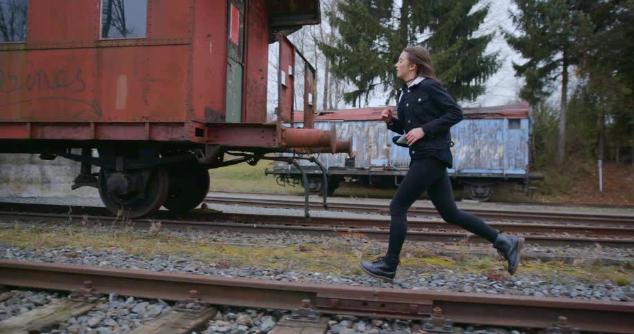 A girl is running next to some train tracks