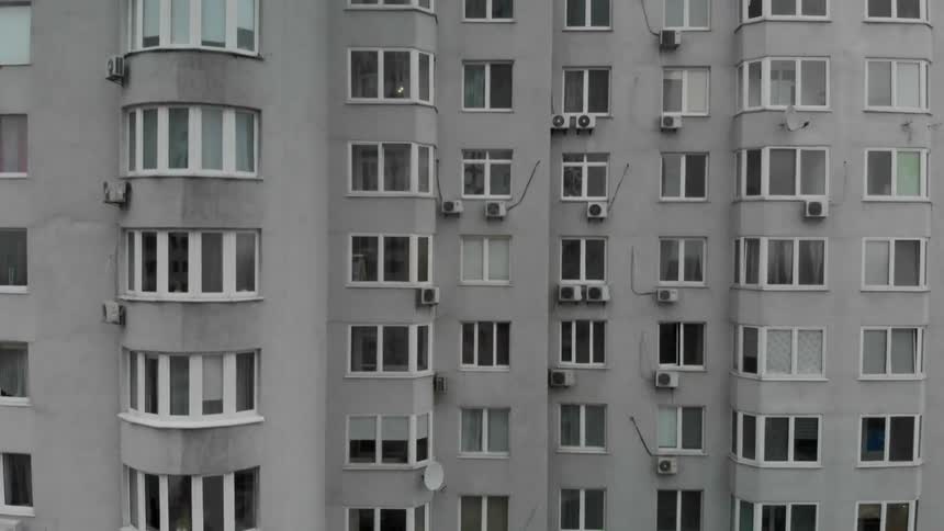 Ac units and satellite dishes occupy exterior building wall near windows
