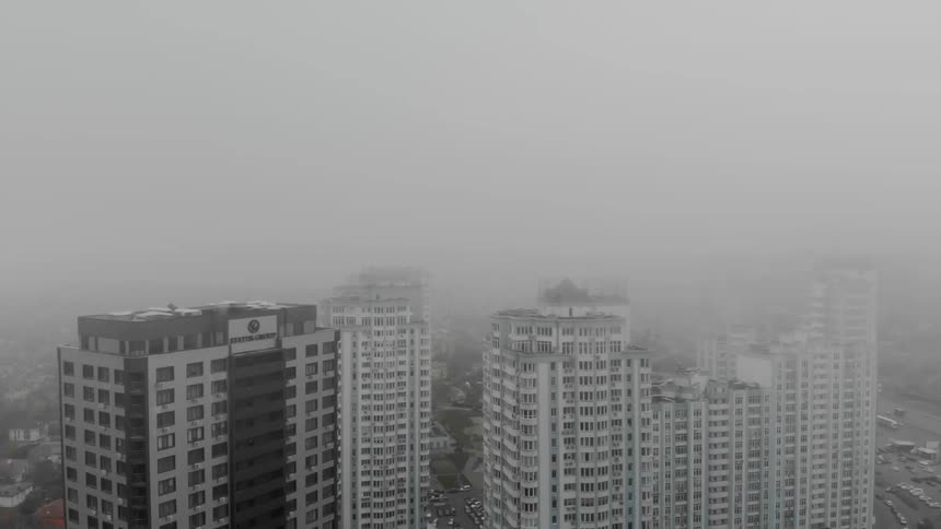 Heavy fog and clouds cover the buildings