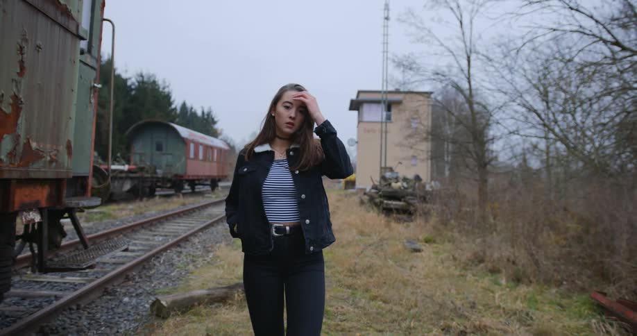 A woman walks beside a rural train and train track