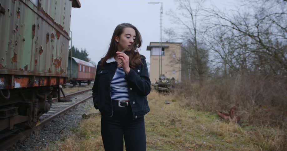 A woman walks beside a row of train tracks and locomotives