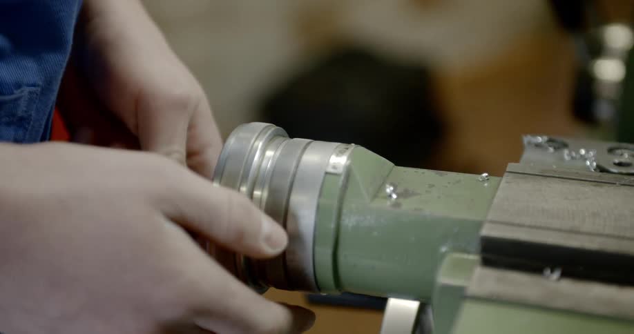 Hand turns a crank on a piece of machinery