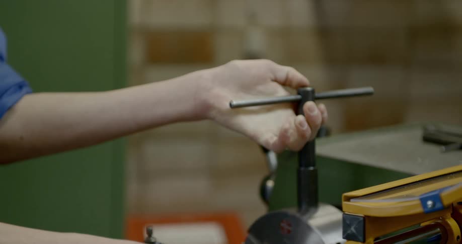 Worker turns levers in a metalworking lathe in a workshop