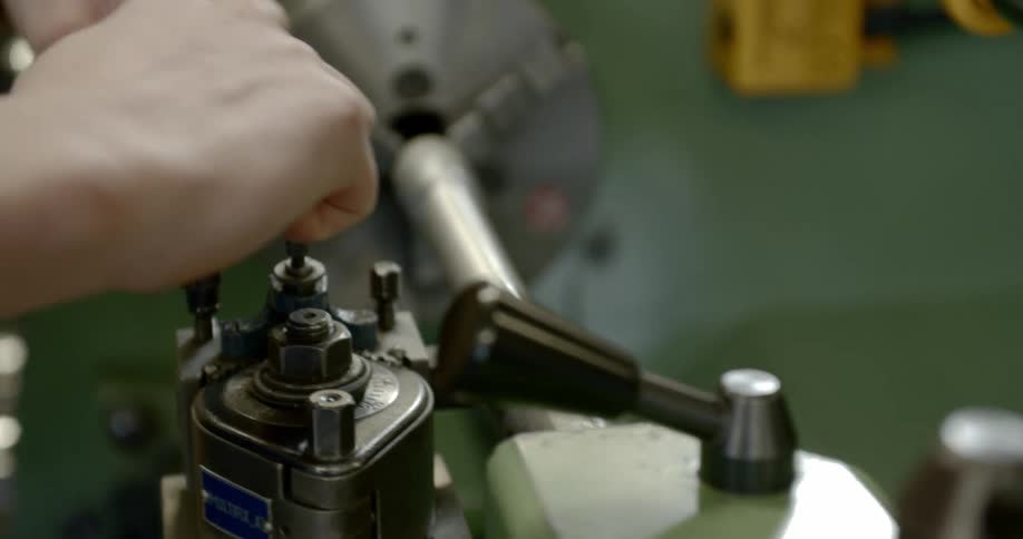 A person uses a tool to tighten the bolts on a machine