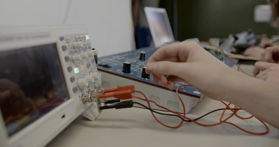Several people are sitting at a table with electronic equipment