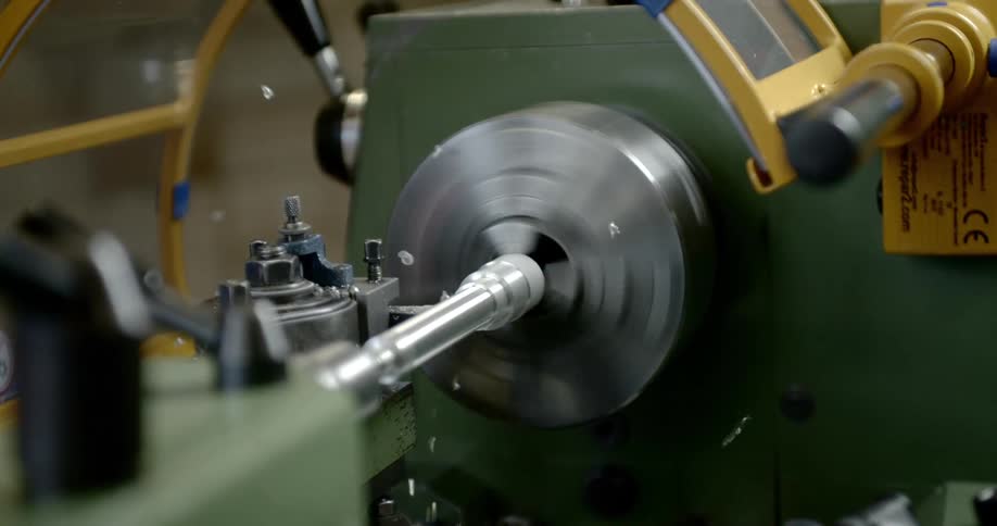 Metalworking lathe spins a metal rod against a cutting tool in a workshop
