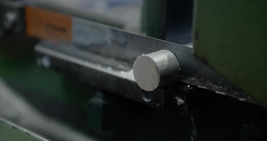 Metalworking machine saws a metal rod in a bench