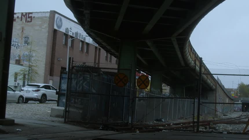 Elevated train trucks run past a city neighborhood marked with graffiti
