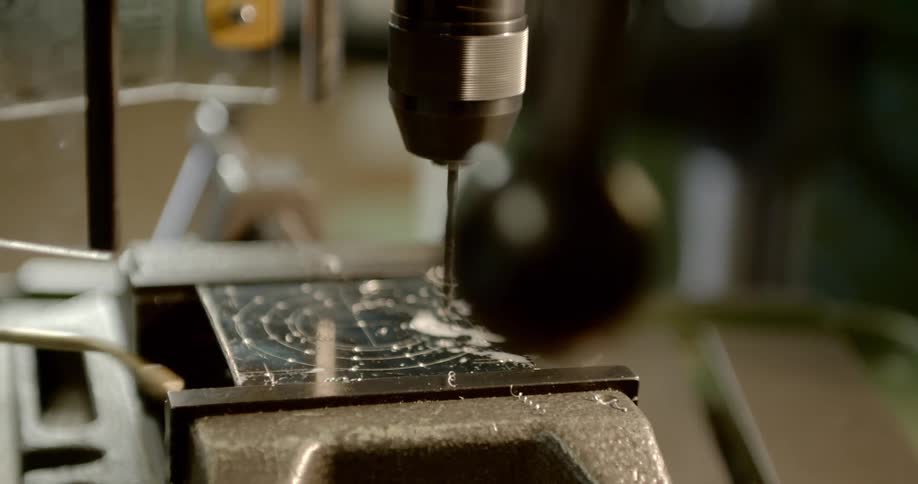 A person using an electric drill to drill a hole in a piece of plastic