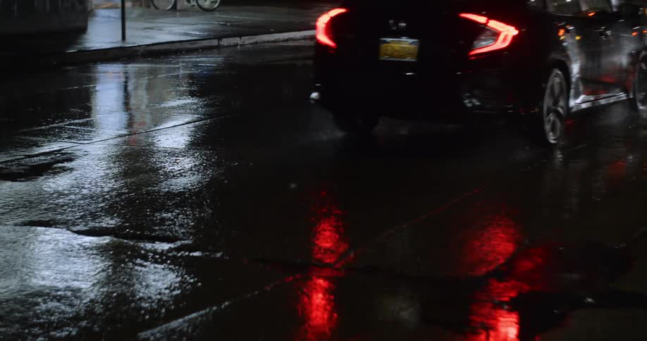 Two cars drive down a rainy street